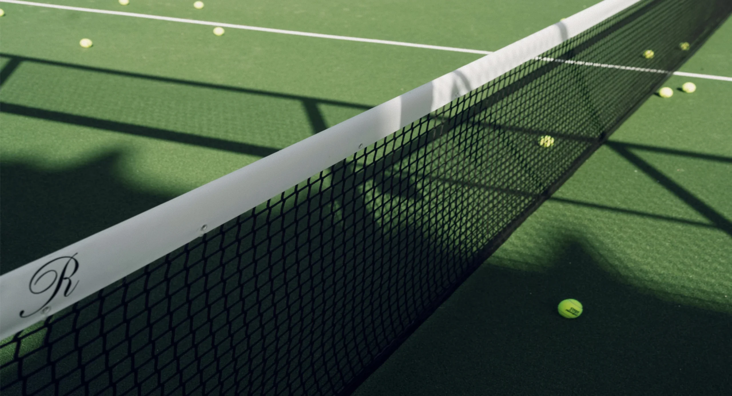 Close-up of a padel net with balls scattered on the court at the ReServe padel facility at The Seagate Delray Racquet Club