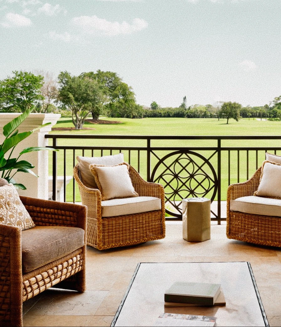 Wicker lounge chairs on the clubhouse deck at The Seagate Delray Golf Club overlooking the lush fairways