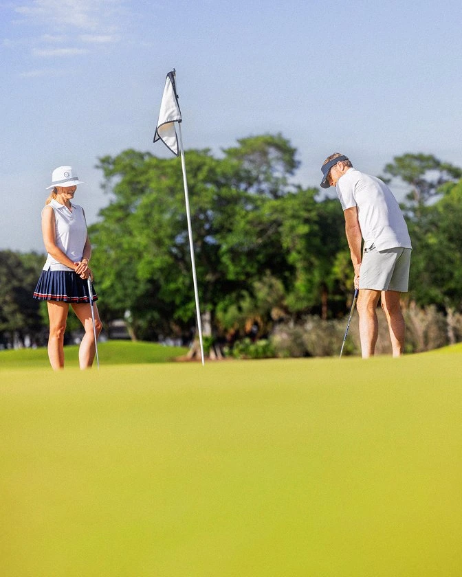 A couple on the putting green at The Seagate Golf Club in Delray Beach, one player lining up a putt at the flag