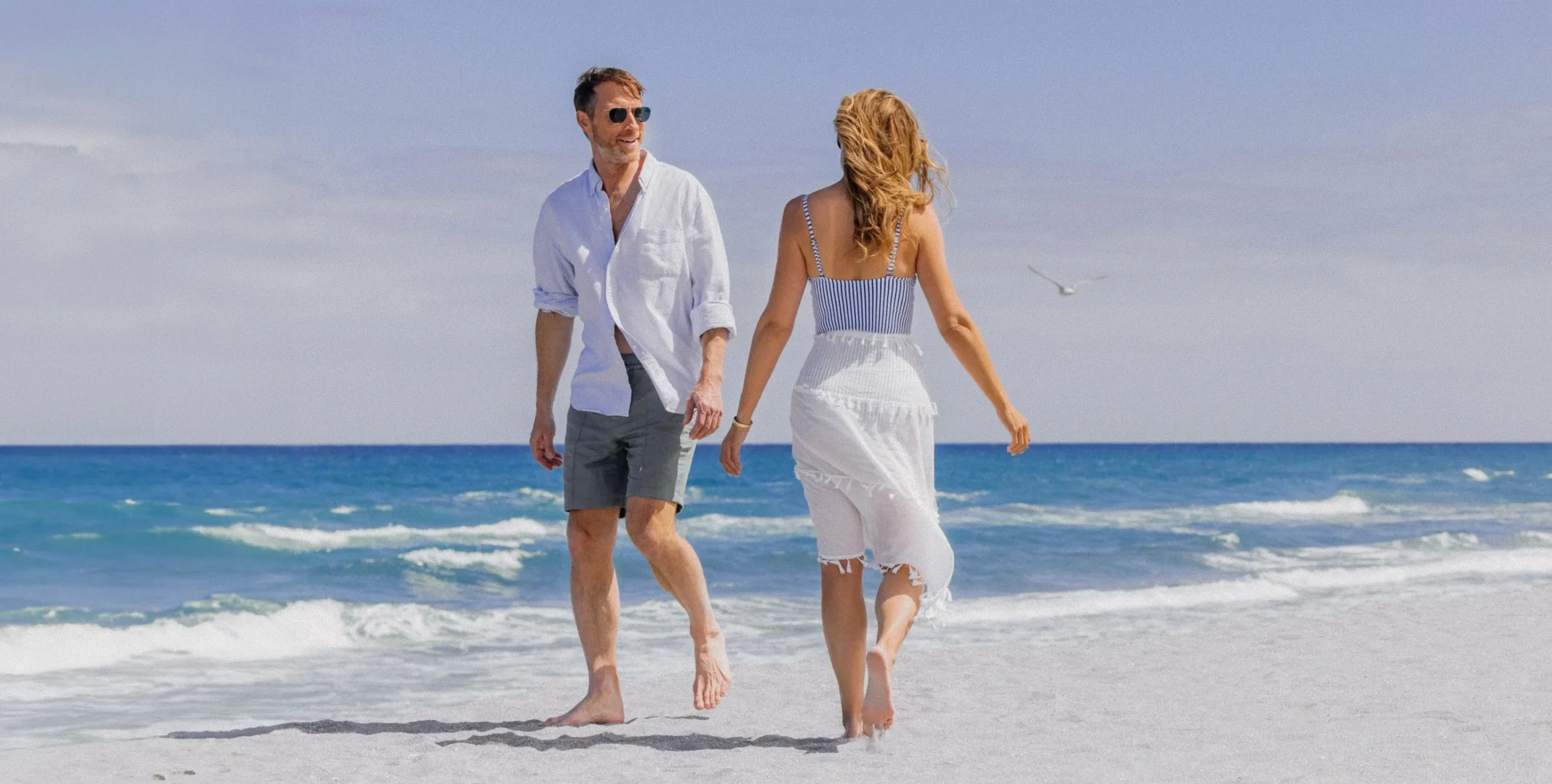 A couple walking hand-in-hand along the shoreline on the private member beach at The Seagate in Delray Beach